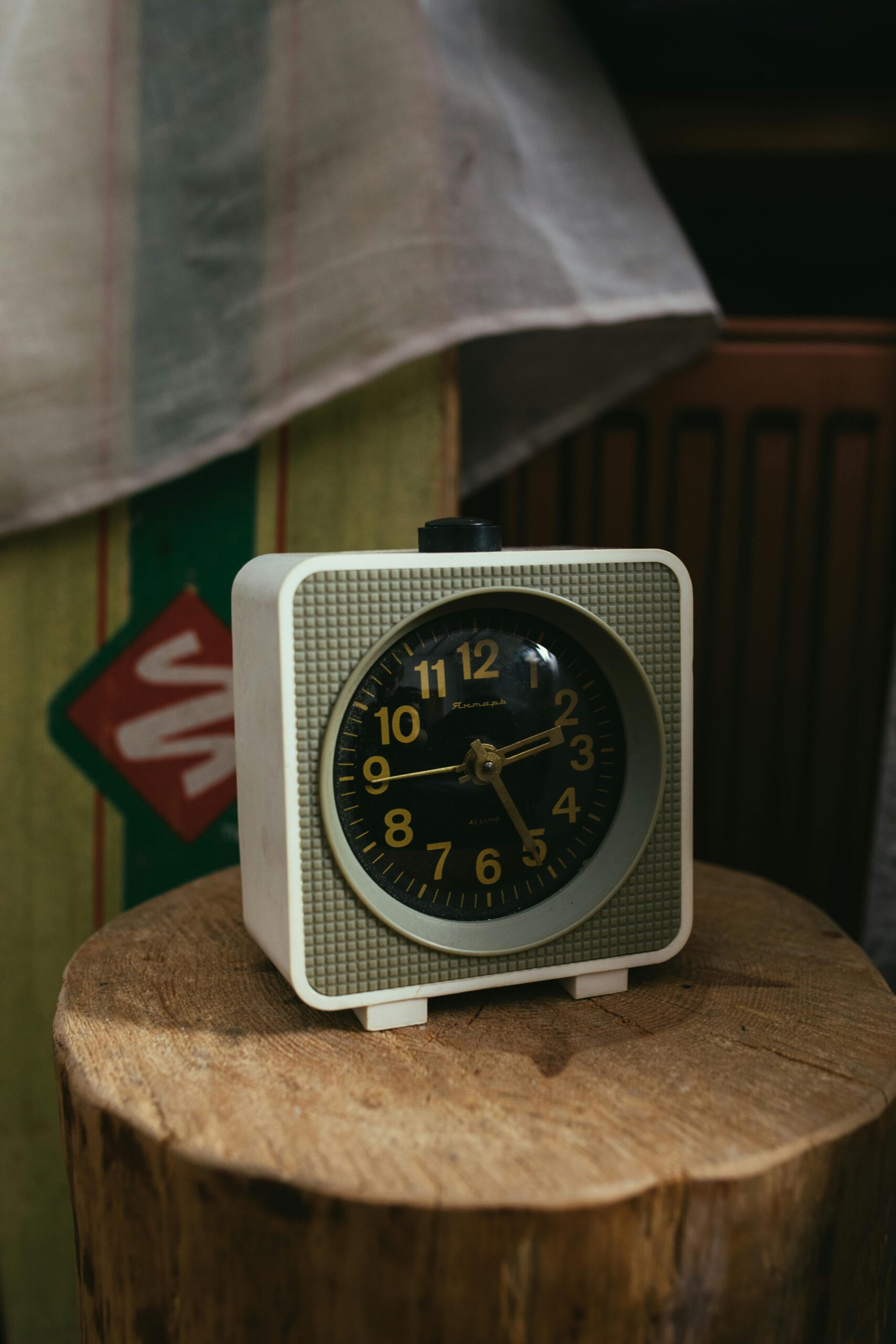 Home Classic analogue alarm clock with a retro design placed on a wooden stump indoors.